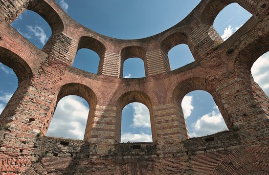 Ruinen der Kaiserthermen in Trier, mit altertümlichen Steinmauern und Bögen, mit blauem Himmel im Hintergrund.