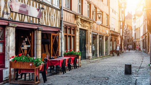 Blick durch eine Gasse in Rouen mit einem Restaurant im Vordergrund und historischen Fachwerkhäusern im Hintergrund