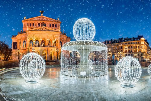 Die Alte Oper in Frankfurt bei Nacht und mit einem weihnachtlich beleuchteten Brunnen im Vordergrund. Es rieselt Schnee
