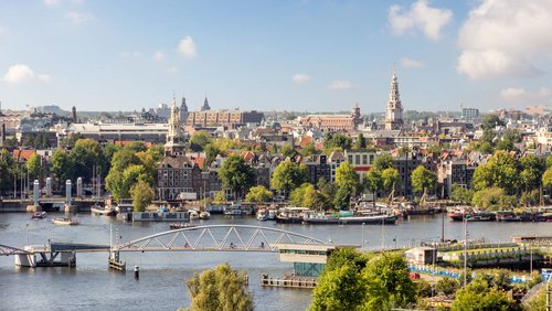 Blick auf Amsterdams historische Skyline mit Kanälen, Brücken, traditionellen Häusern und Kirchtürmen bei klarem Himmel