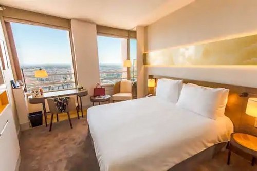 Modernes Zimmer des Hotel Radisson in Lyon, mit Doppelbett, Schreibtisch und großen Panoramafenstern.
