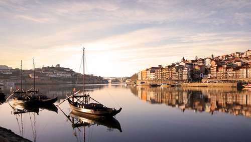 Blick auf die historische Altstadt von Porto mit bunten Häusern am Fluss Douro, im Hintergrund die ikonische Brücke Dom Luís I.