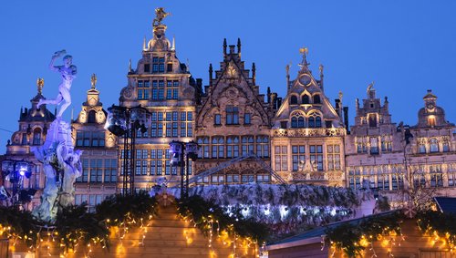Weihnachtlich beleuchtete historische Fassaden am Grote Markt in Antwerpen bei Abenddämmerung mit dem Brabo-Brunnen links im Bild
