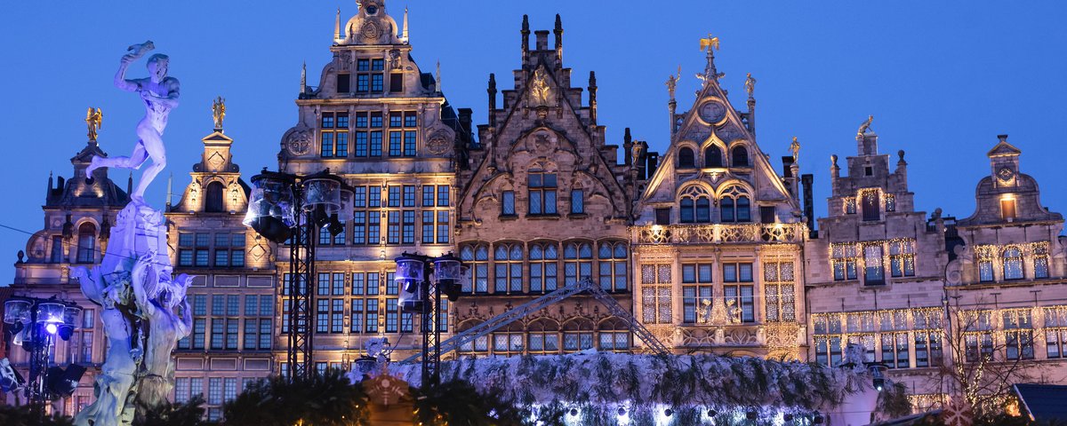 Weihnachtlich beleuchtete historische Fassaden am Grote Markt in Antwerpen bei Abenddämmerung mit dem Brabo-Brunnen links im Bild