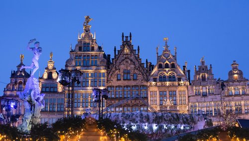 Weihnachtlich beleuchtete historische Fassaden am Grote Markt in Antwerpen bei Abenddämmerung mit dem Brabo-Brunnen links im Bild