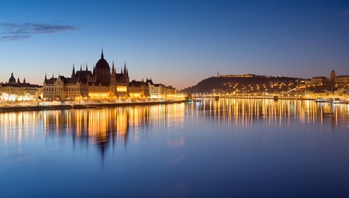 Blick auf das parlamentsgebäude in Budapest bei Nacht beleuchtet, mit der Stadt im Hintergrund.