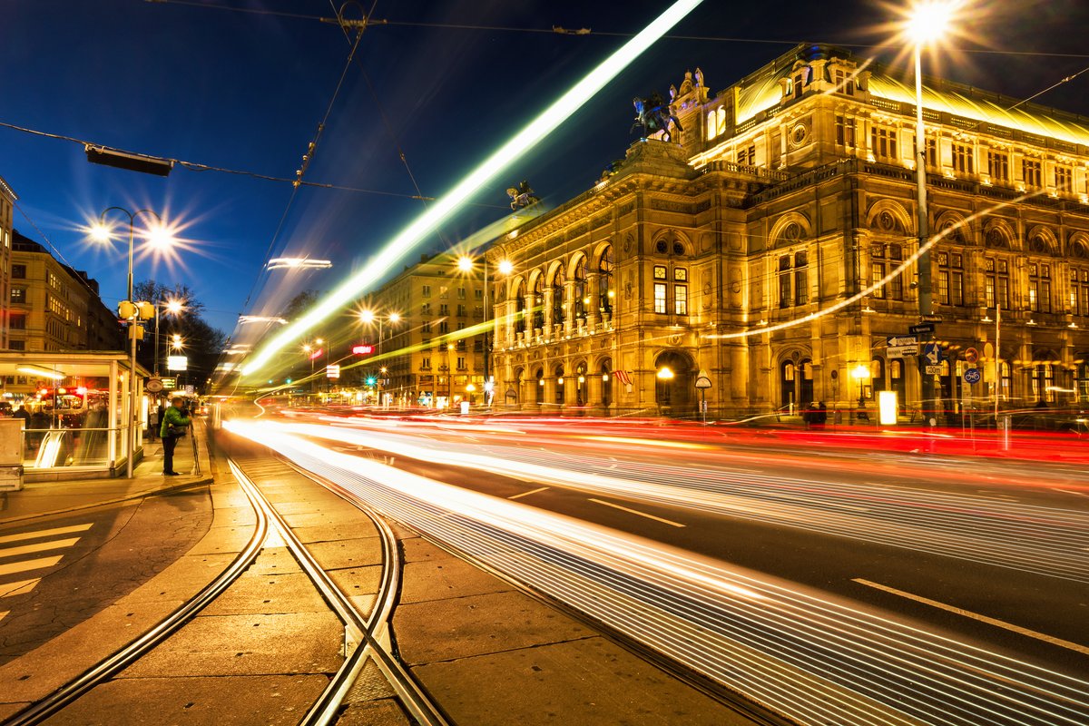 Das Wiener Opernhaus bei Nacht, beleuchtet mit goldenen Lichtern, umgeben von historischen Gebäuden und einem klaren Nachthimmel.